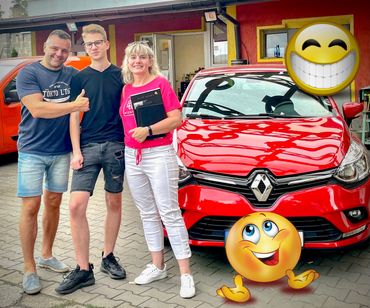 Uśmiechnięci ludzie stoją przy czerwonym samochodzie Renault clio