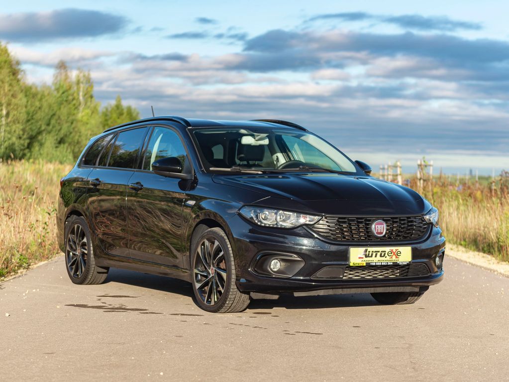 Fiat Tipo kombi w kolorze czarnym stoi skosem na wąskiej drodze asfaltowej w plenerze
