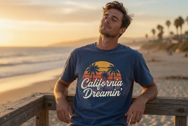 Man wearing a California Dreamin' t-shirt on a beach at sunset.