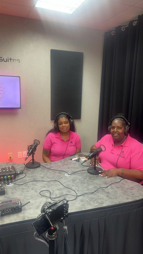 Two women in pink shirts recording a podcast in a studio.