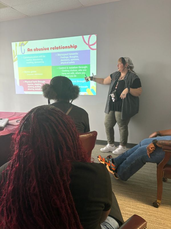 A person giving a presentation on abusive relationships to an attentive audience.