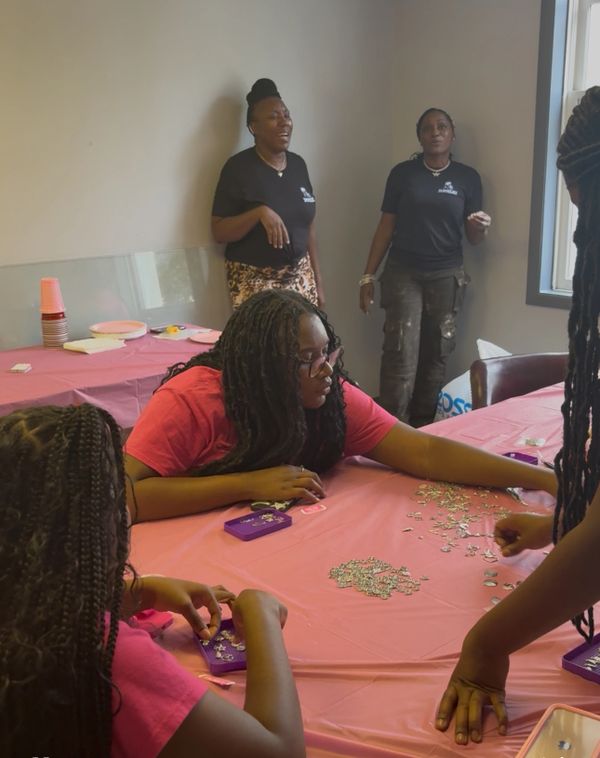 People gathered around a table working on a craft project with jewelry pieces.