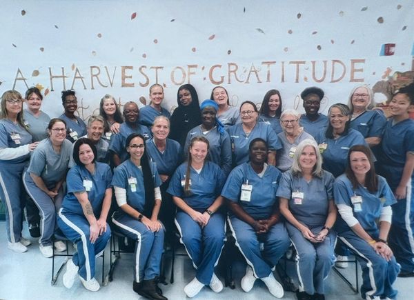 Group of healthcare workers smiling in front of a gratitude-themed wall.