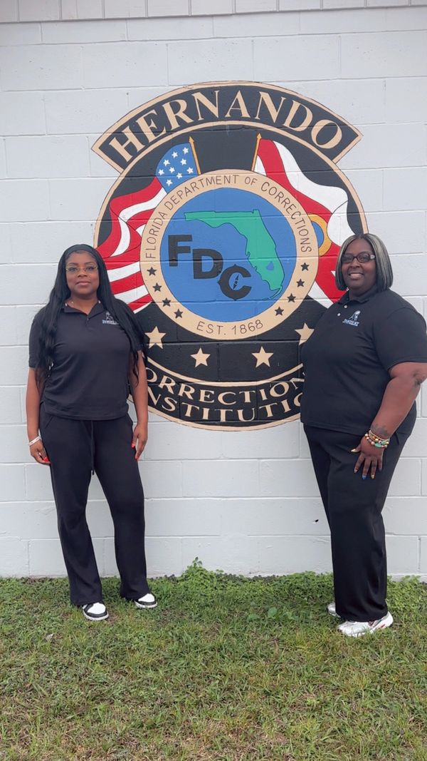 Two women standing in front of Hernando Correctional Institution mural.