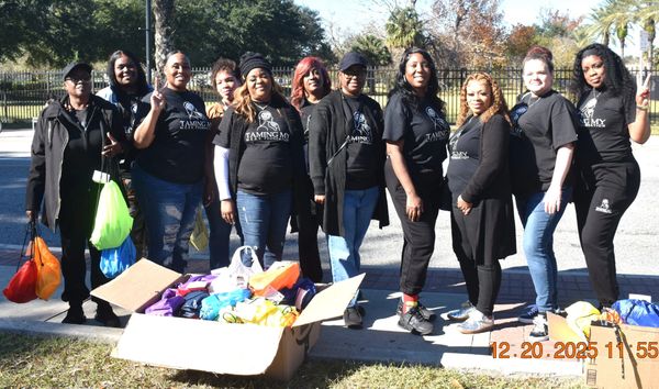 Group of women wearing matching foundation shirts with donation bags outdoors.