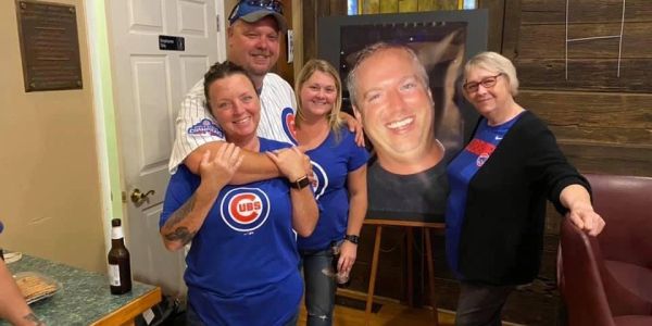 Group photo with Chicago Cubs fans and a large smiling face poster.