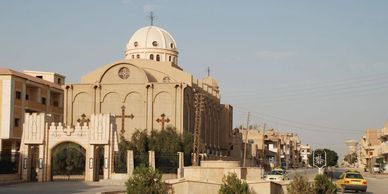 A large beige church with a dome in an urban area.