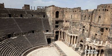 Ancient Roman amphitheater with stone seating and columns.