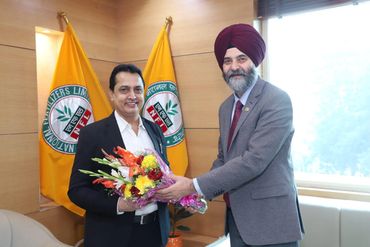 Two men exchanging a bouquet of flowers in an office.