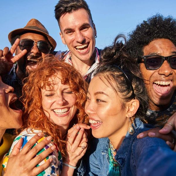 A diverse group of friends happily taking a selfie together outdoors.