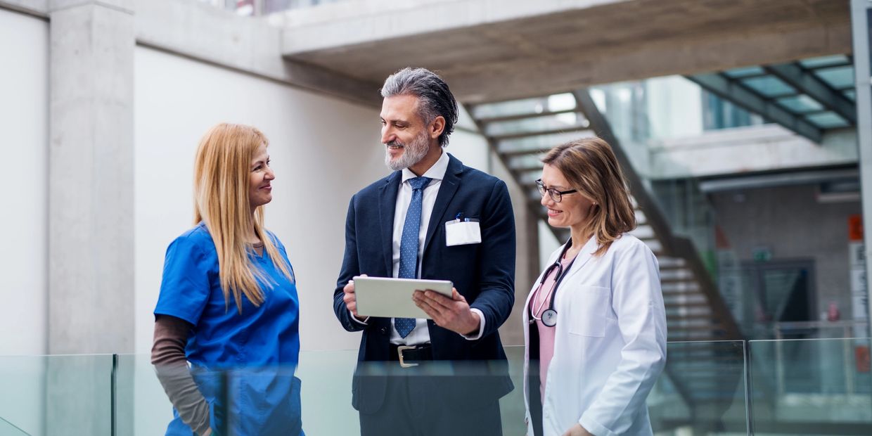 Three healthcare professionals discussing with a tablet in a modern hospital.