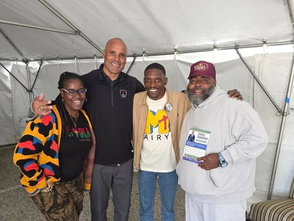 Four people standing together under a tent, smiling for a photo.
