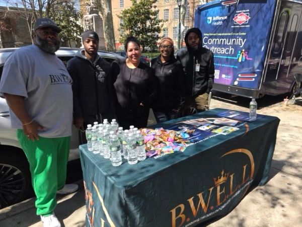 Group at a community outreach event with B.WELL table and snacks.