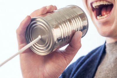 Man talking into a can with a string.  Communication.