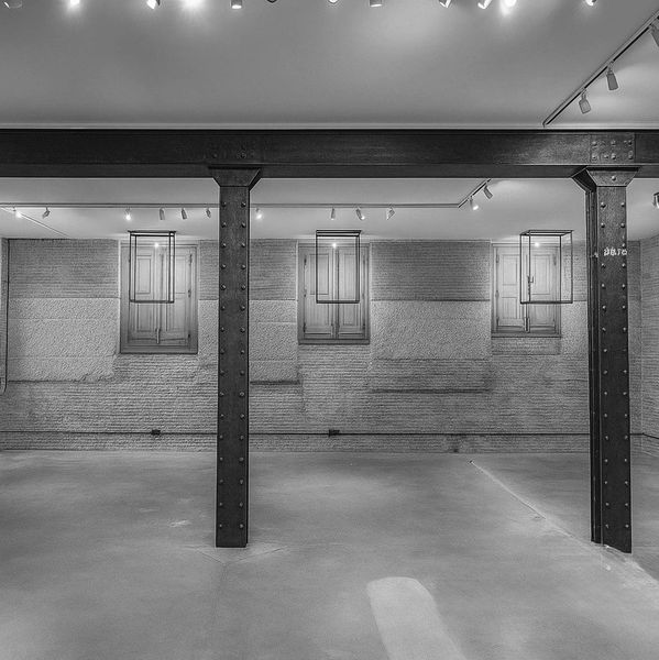 Empty industrial-style room with metal beams and wooden windows.