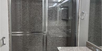 Ducha con puerta corrediza de vidrio texturizado.
