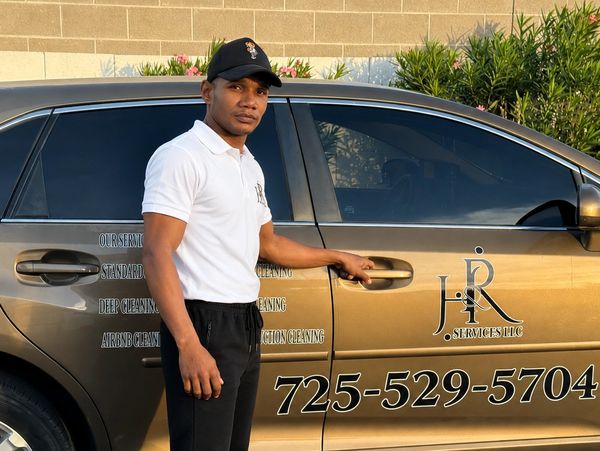 H&R Services LLC team member next to a wrapped company vehicle with phone number
