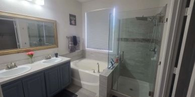 Baño moderno con ducha, bañera y lavabo doble.