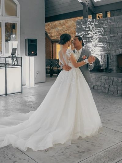 Bride and groom share a dance in a rustic wedding venue.