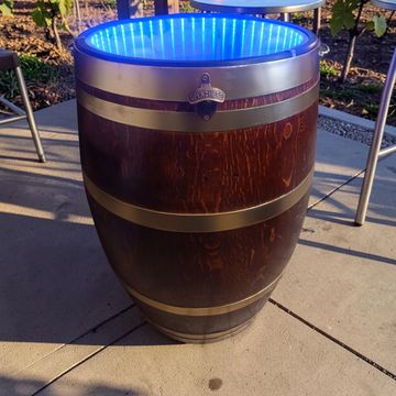Wooden barrel cooler with blue LED lights in vineyard.