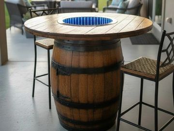 Outdoor barrel table with blue-lit fire pit and chairs.