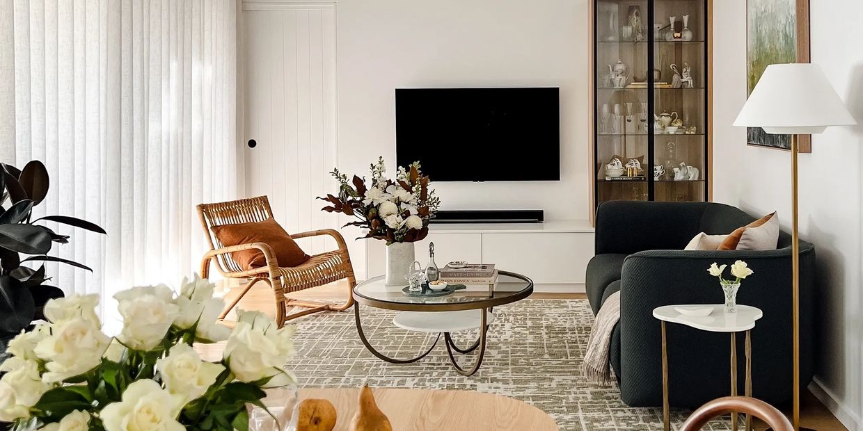 Modern living room with clean-lined TV joinery with black framed glass doors. Brass coffee table 