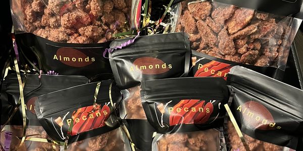 Assorted packaged almonds and pecans in a gift box with decorative shredded paper.
