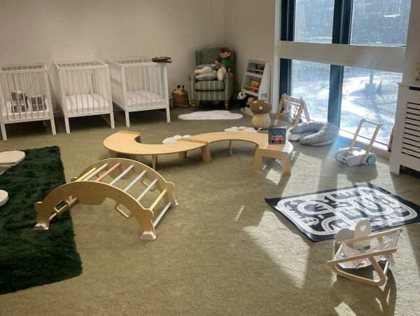 Bright and spacious nursery playroom with various toys and cribs.