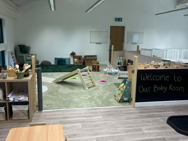 Indoor baby playroom with toys and a welcome sign.