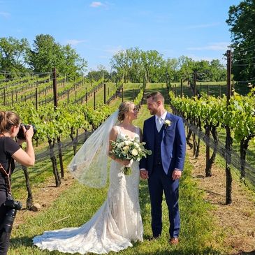 Bride and groom posing for photos in a vineyard.