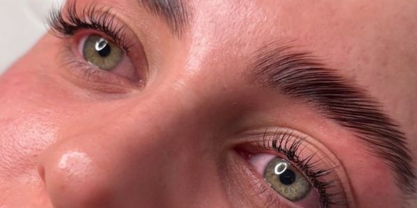 Close-up of green eyes with long lashes and groomed eyebrows.