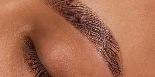 Close-up of a well-groomed eyebrow and closed eye with long eyelashes.