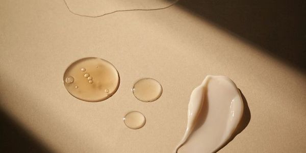 Different skincare product textures on a beige surface with light and shadow.