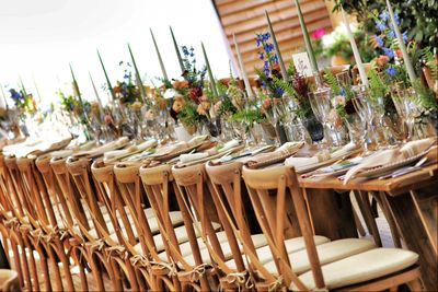 Elegant long dining table set with wooden chairs and floral centerpieces for an event.