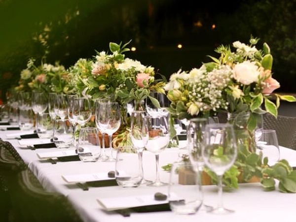 Elegant table setting with floral centerpieces and glassware for an outdoor event.