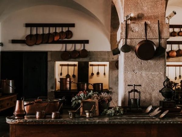 Rustic kitchen with copper pots and pans displayed on walls and counters.