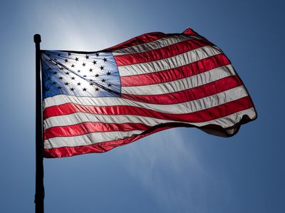 United States flag waving against a clear blue sky.