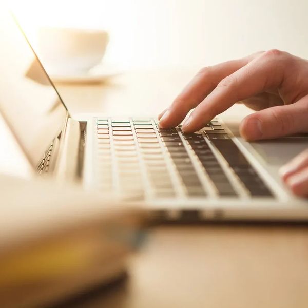 Person typing on a laptop keyboard in a softly lit environment.