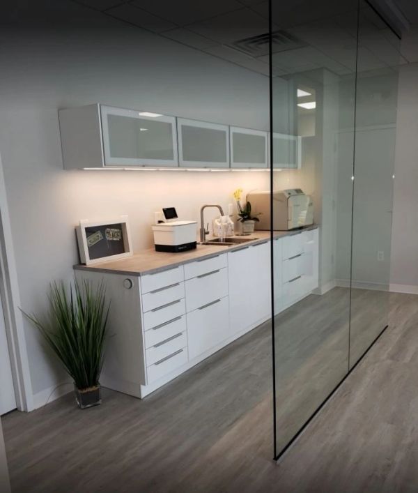 Modern kitchenette with white cabinets and glass partition.
