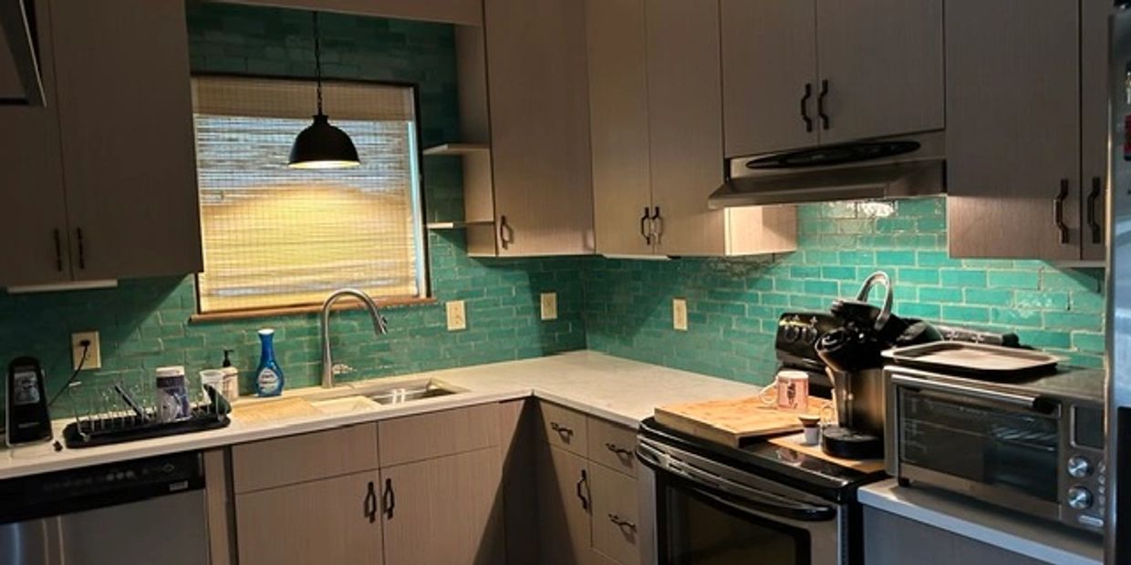 Modern kitchen with teal backsplash and wooden cabinets.