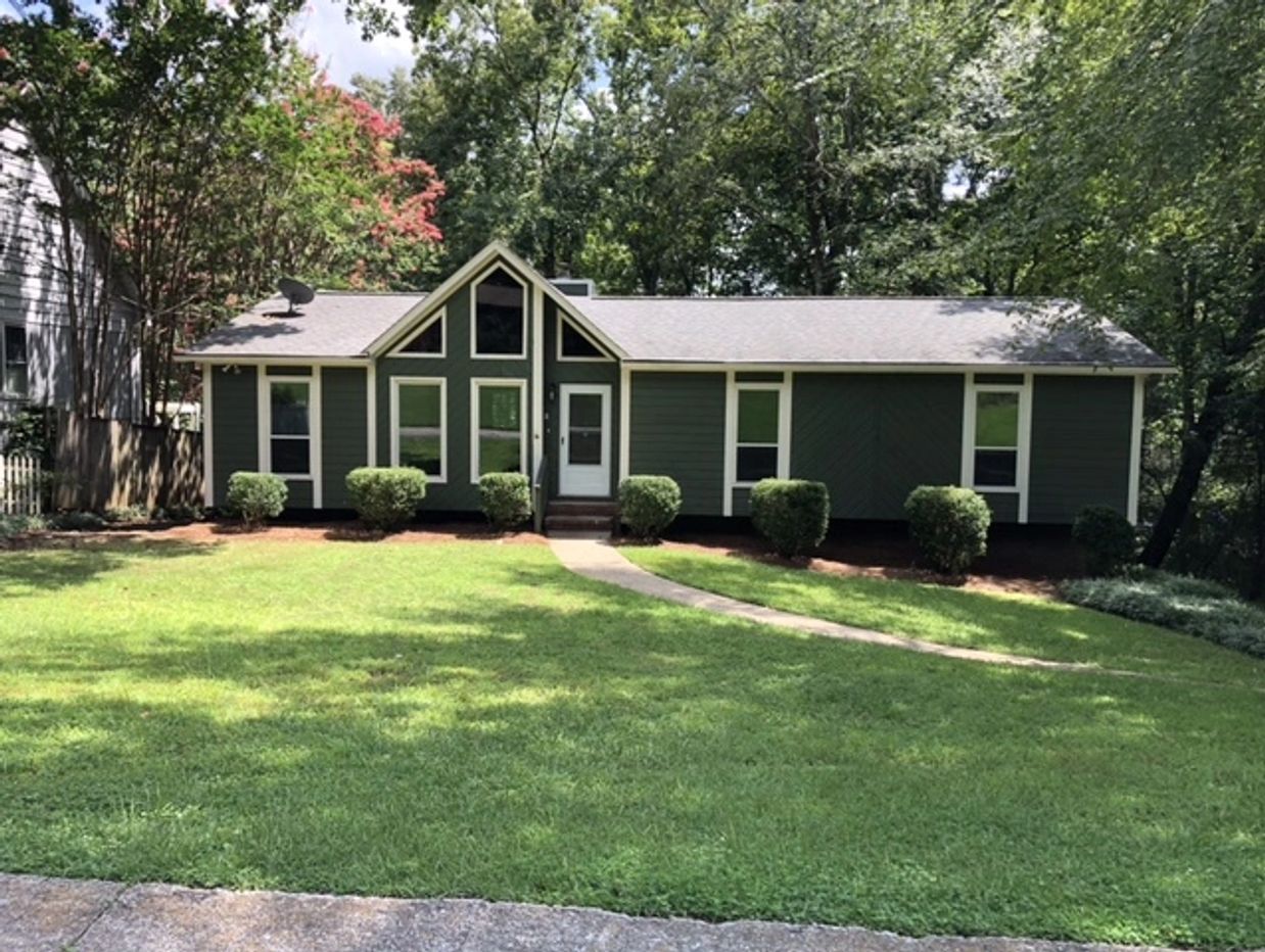 Cozy single-story house with green exterior and a large yard.