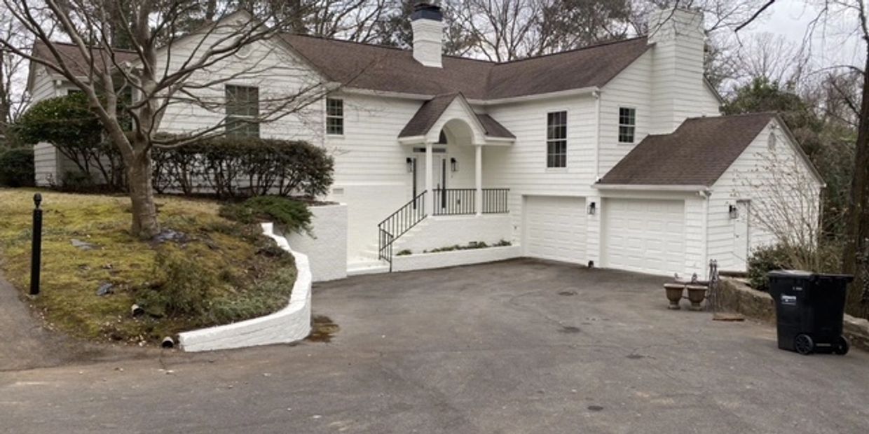 White house with a large driveway and garage.