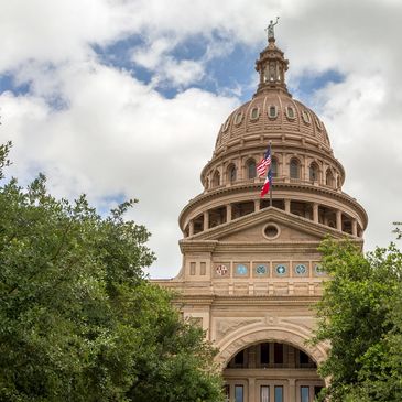 The dome of a historic capitol building with flags flying.