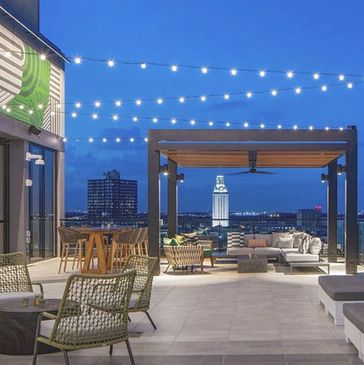 Rooftop lounge with city view and string lights at dusk.