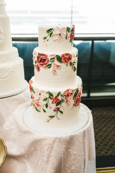 Elegant three-tier white cake adorned with pink and red floral decorations.