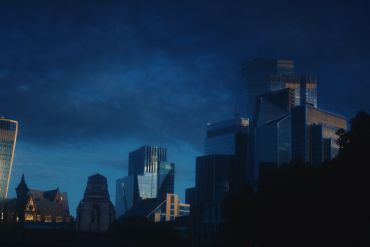 City skyline at dusk with modern skyscrapers silhouetted against a darkening sky.