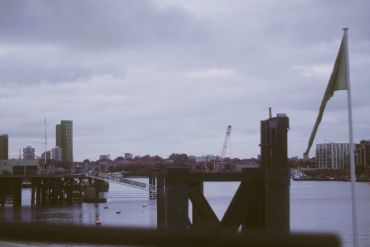 A cloudy day at a harbor with docks and city buildings in the distance.