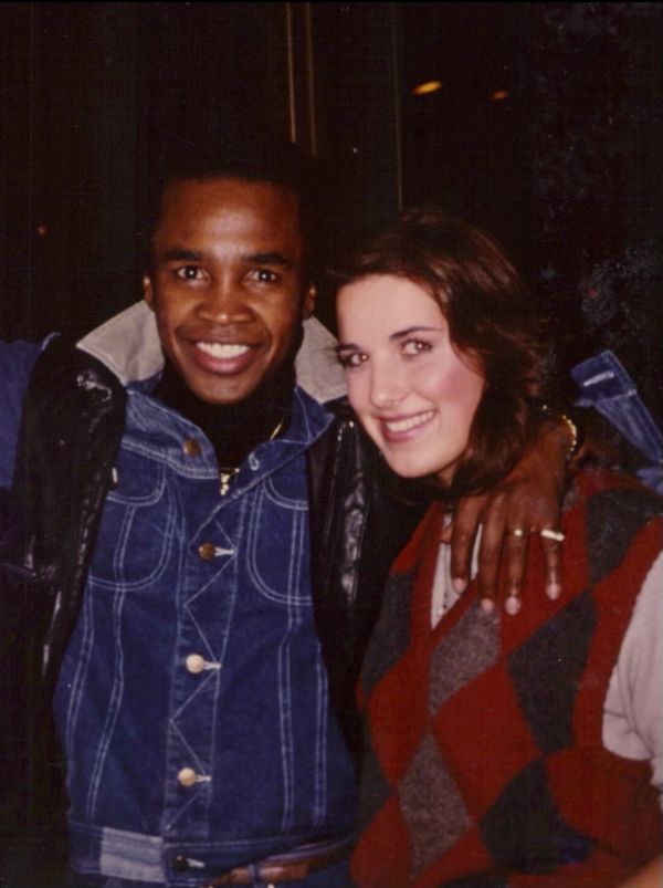 Two friends smiling with arms around each other.