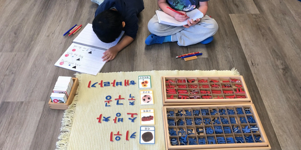 Two children engaged in a Korean language learning activity on the floor.