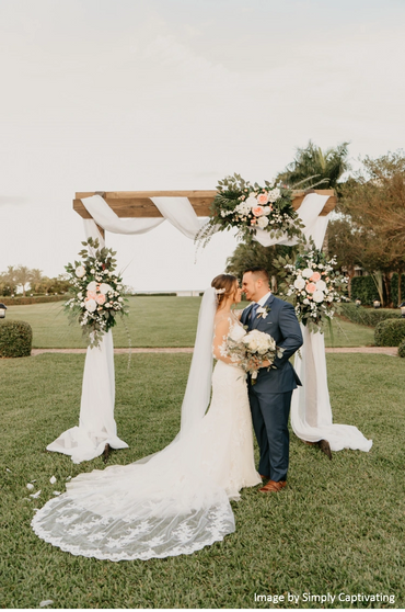 Bride and groom with arch at the garden lawn. 